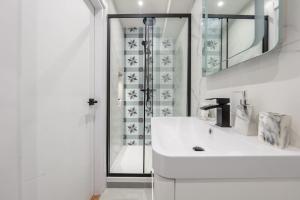 een witte badkamer met een wastafel en een douche bij 3 West London Brand New Loft in Londen