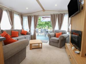 ein Wohnzimmer mit einem Sofa, Stühlen und einem TV in der Unterkunft Stanley's Lodge, Foxburrow Hang in Great Yarmouth
