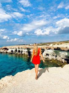 a woman in a red dress walking on the beach at Tsokkos Protaras Beach Hotel in Protaras