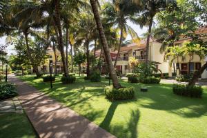 a lawn with palm trees in front of a building at Radisson Blu Resort, Goa in Cavelossim