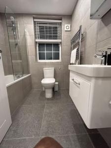 a bathroom with a toilet and a sink and a window at 1 bed high quality modern flat in Edgware