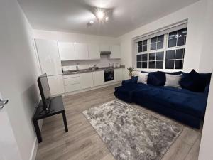 a living room with a blue couch and a kitchen at 1 bed high quality modern flat in Edgware