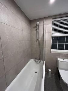 a bathroom with a bath tub and a toilet at 1 bed high quality modern flat in Edgware