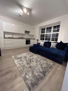 1 bed high quality modern flat في إدجوير: غرفة معيشة مع أريكة زرقاء ومطبخ