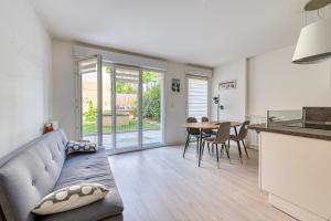 ein Wohnzimmer mit einem Sofa und einem Tisch in der Unterkunft Le St Gratien - Appartement avec jardin in Épinay-sur-Seine