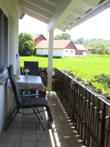 a table and chairs on a porch with a view of a field at Gästehaus Reisacher - Mehrbettzimmer in Peiting