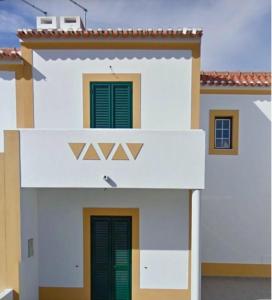 a white house with green shutters on it at Oliveira Beach House in Longueira