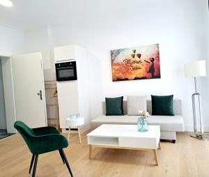 a living room with a white couch and a green chair at Stadtpalais am Schöntal in Aschaffenburg