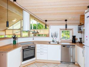 eine Küche mit weißen Schränken sowie Holzdecken und -fenstern in der Unterkunft 10 person holiday home in L kken in Løkken