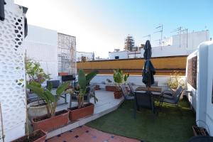 einen Balkon mit Stühlen, Tischen und Pflanzen auf einem Gebäude in der Unterkunft The Terrace, dúplex con terraza privada in Sevilla