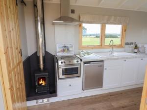 a kitchen with a stove with a fire in it at Shepherds Hut in Scunthorpe