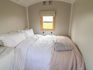 a white bed in a small room with a window at Shepherds Hut in Scunthorpe