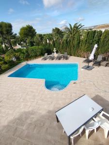 a swimming pool with chairs and a table next to it at Apartments in a "VILLA VISTA JAVEA" in Jávea