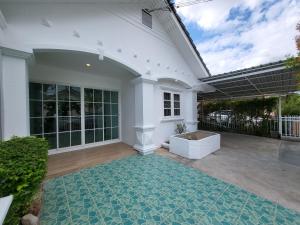 a white house with a patio with a rug at Minimal homey 3BR near Mee Chok plaza in Chiang Mai