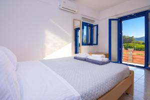 a bedroom with a white bed and a large window at Blue Breeze in Milatos