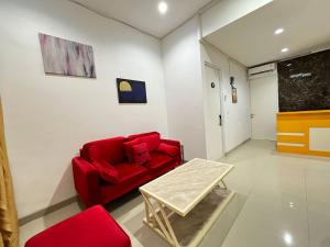 sala de estar con sofá rojo y mesa en RedDoorz at Ring Road II Area Manado, en Paniki