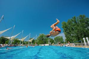 uma pessoa a saltar para a água numa piscina em Balatontourist Füred Camping & Bungalows em Balatonfüred