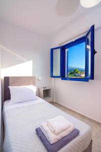 a white bedroom with a bed and a window at Blue Breeze in Milatos