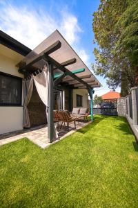 een pergola in een achtertuin met een gazon bij Hori Homes Apartman in Siófok