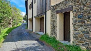 un edificio de piedra con dos puertas de garaje junto a una carretera en Casa con jardín cerca de Llívia, en Estavar