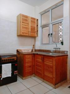 a kitchen with wooden cabinets and a sink and a window at Coastal Apartments KMA Mtwapa,Kilifi by Nest & Nomad in Mtwapa