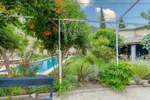 un jardín con piscina y un banco azul en Rose Thé - Maison de village dans le Lubéron, en Robion en Luberon