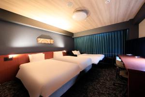 a hotel room with two beds and a desk at Richmond Hotel Yokohama-Bashamichi in Yokohama