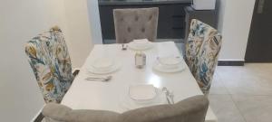 uma mesa com duas cadeiras e uma mesa branca com pratos em City Haven Accommodation-Two bedroom Apartment em Nairobi