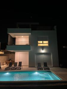 - une piscine en face d'une maison la nuit dans l'établissement New Lux Villa Aardiel jaccuzi pool wiew, à Kaštela