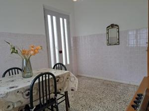 ein Esszimmer mit einem Tisch und einer Blumenvase darauf in der Unterkunft Casa Gelsomino in Rimini