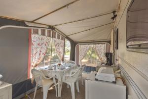 a dining room with a table and chairs in a trailer at Camping du Grand Batailler in Bormes-les-Mimosas