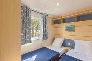 a small bedroom with two beds and a window at Camping du Grand Batailler in Bormes-les-Mimosas