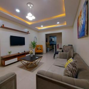 Ziroc Apartments Lekki Phase 1 في لاغوس: غرفة معيشة مع أريكة وتلفزيون بشاشة مسطحة