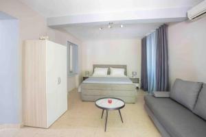 a bedroom with a bed and a couch and a table at Anthia private studio a breath away from beaches in Agios Nikitas