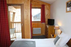 Schlafzimmer mit einem Bett und einem Balkon mit einem TV in der Unterkunft Résidence Alpina Lodge by Valdiski in Val dʼIsère