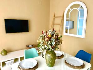 una mesa con platos y un jarrón con flores. en Apartamento La Rosa - RECIÉN REFORMADO en Córdoba