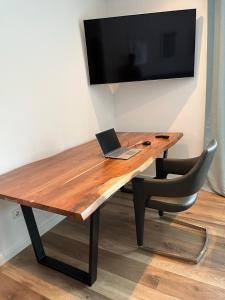 a wooden desk with a laptop and a television at Bergpanorama - Suite Willingen in Willingen