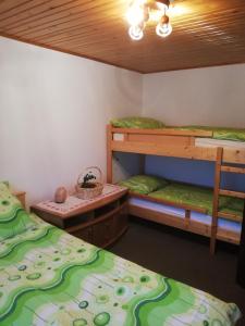 Cette chambre comprend 2 lits superposés et une table. dans l'établissement Apartma pri Bregarju, à Bohinj