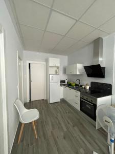 a kitchen with white appliances and a white chair at Apartamento Gabarron in Mula