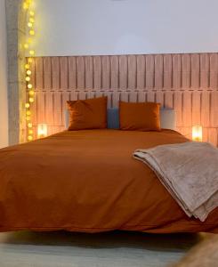 ディジョンにあるLOFT Spa Gare Cité Gastronomique Dijonのベッドルーム1室(大型ベッド1台、オレンジのシーツ、照明付)