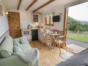 a living room with a couch and a kitchen with a table at Tan Y Castell Shepherds Hut in Llangollen