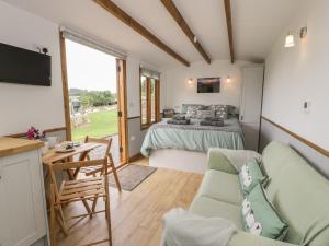 a room with a bedroom and a bed and a table at Tan Y Castell Shepherds Hut in Llangollen