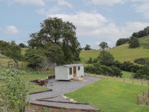a small white shed in the middle of a field at Tan Y Castell Shepherds Hut in Llangollen