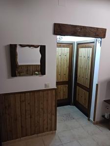 Habitación con puertas de madera y TV en la pared. en Corazón de Mágina, en Bedmar
