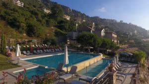 a swimming pool with chairs and umbrellas next to a mountain at Cherry Blossom Boutique Hotel in Bḩamdūn
