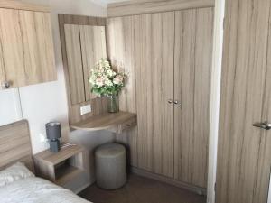 a small bedroom with a vase of flowers on a cabinet at Poppy 57, Oakdene Forest Park in Bournemouth