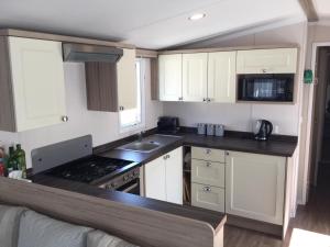 a kitchen with white cabinets and a black counter top at Poppy 57, Oakdene Forest Park in Bournemouth