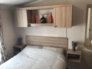 a bedroom with a bed with red bottles on the wall at Poppy 57, Oakdene Forest Park in Bournemouth
