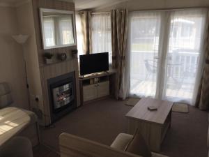 a living room with a television and a fireplace at Poppy 57, Oakdene Forest Park in Bournemouth