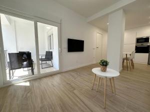 a white living room with a table and a tv at Apartamento Galiria, Pals in Pals